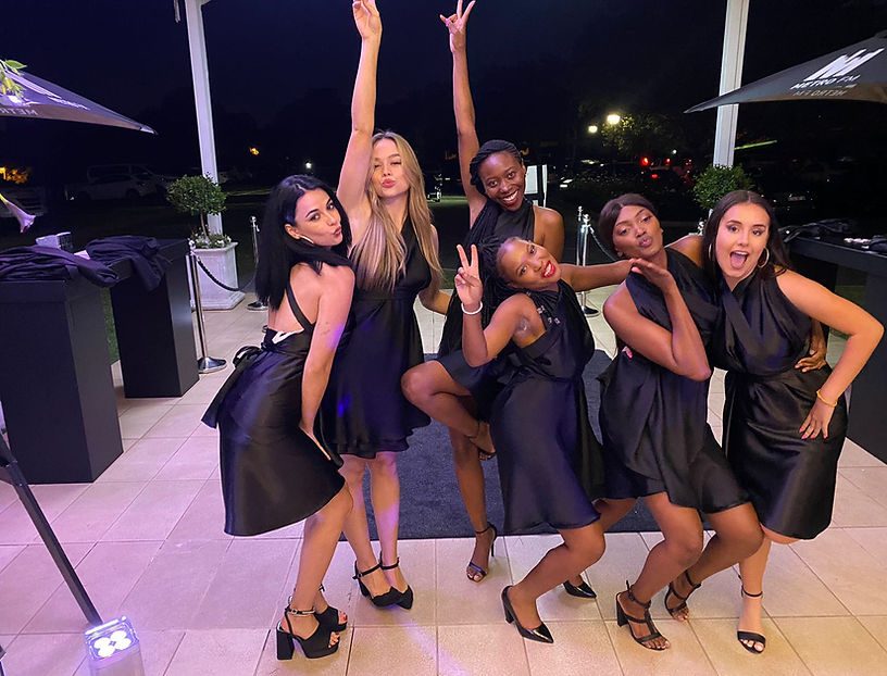 Energetic group of promo girls joyfully celebrating the success of an event, radiating confidence and excitement.